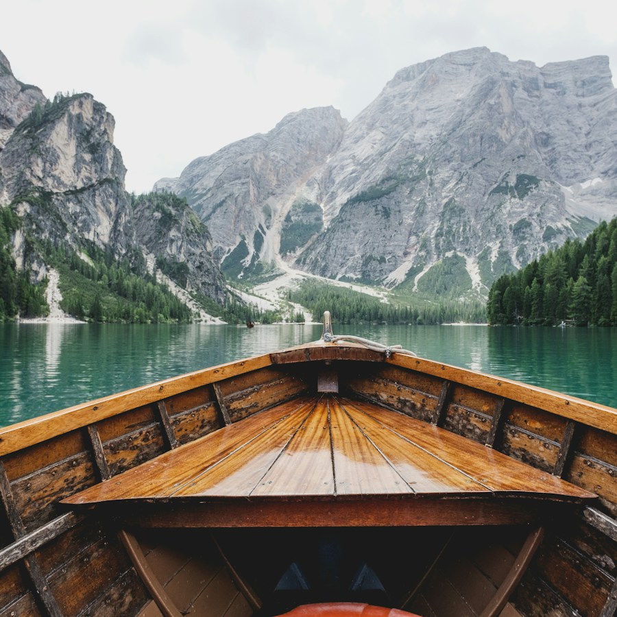 A wooden boat on a turquoise lake surrounded by mountains
